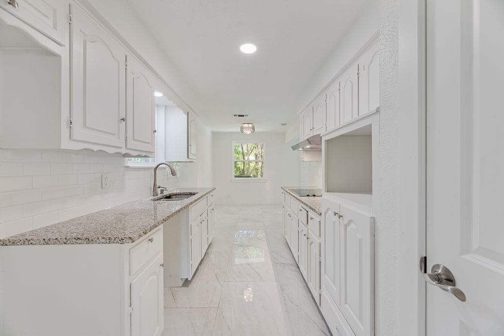 Kitchen featuring white cabinetry, stone-finish countertops, subway tile backsplash, recessed lighting, and large-format tile flooring