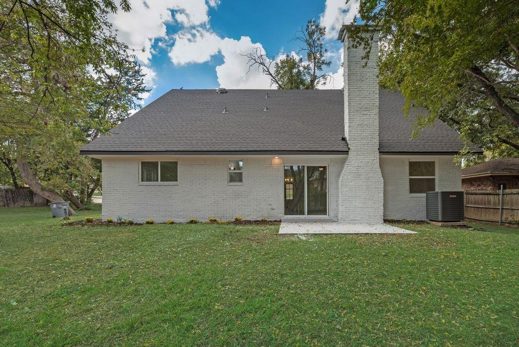 Painted brick exterior featuring a prominent masonry chimney, sliding glass doors, and a concrete patio