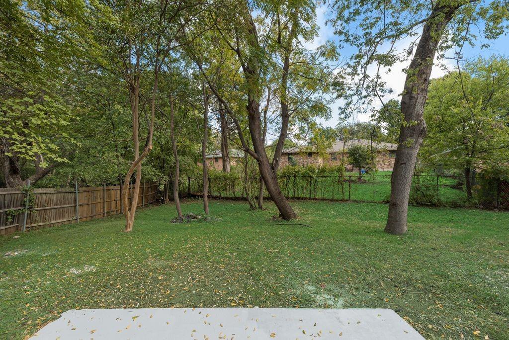 Spacious backyard featuring a concrete patio, mature trees, and perimeter wood fencing Spacious backyard featuring a concrete patio, mature trees, and perimeter wood fencing