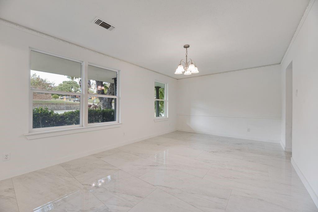 Large-format polished tile flooring, multi-pane windows, crown molding, chair rail trim, and a multi-arm chandelier Large-format polished tile flooring, multi-pane windows, crown molding, chair rail trim, and a multi-arm chandelier