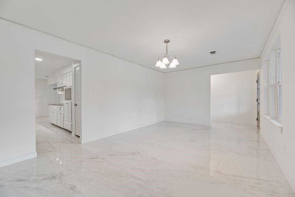 grand room could be dining room and sitting room. featuring large-format tile flooring, neutral wall finishes, and a multi-arm chandelier