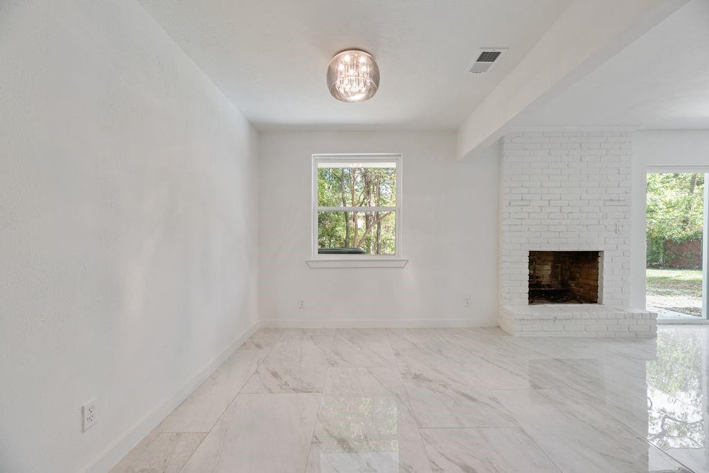 White-painted brick fireplace, polished stone-finish tile flooring, and a spherical flush-mount light fixture
