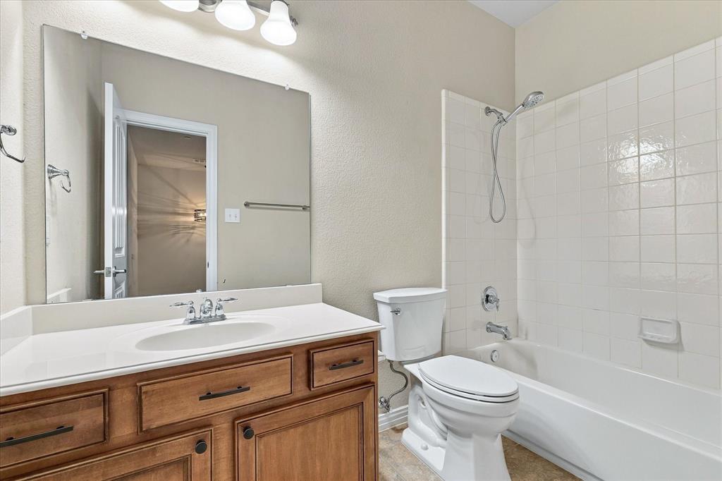 Secondary bathroom with a tub and shower combination, spacious vanity, and a NEW toilet.
