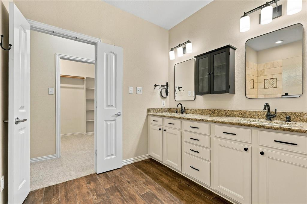 Spacious primary bath with dual vanities, granite countertops, NEW lighting, a linen closet, and a Texas sized walk-in closet that has the space you have always wanted!