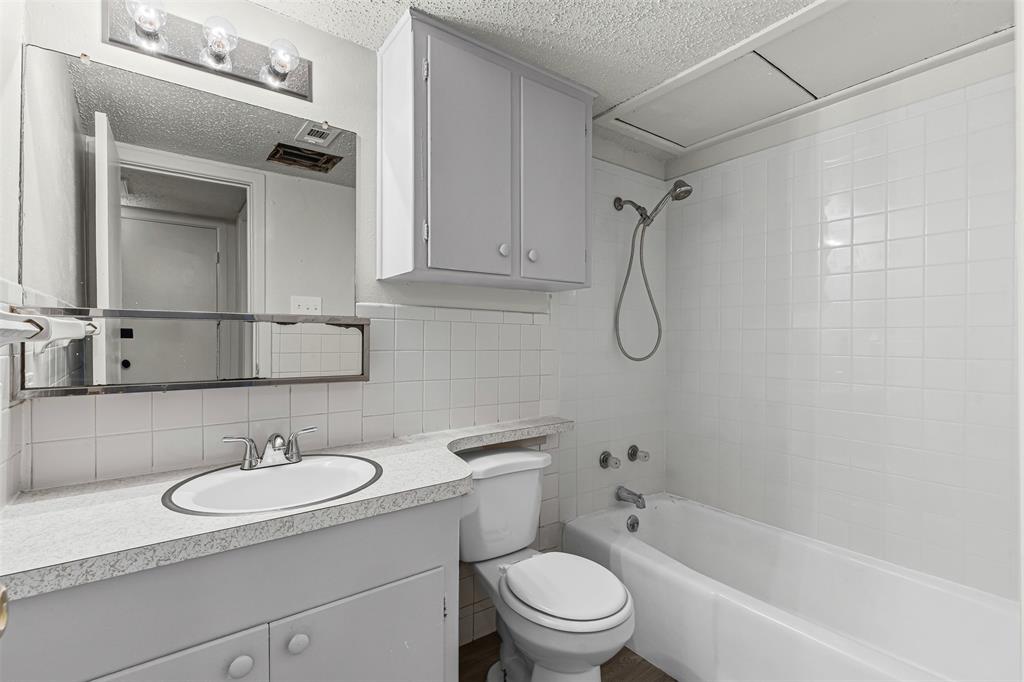 Full bath with vanity, shower / washtub combination, tasteful backsplash, a textured ceiling, and tile walls