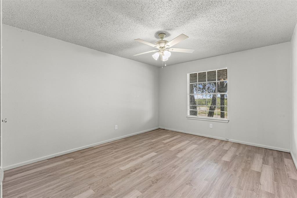 Unfurnished room with a textured ceiling, light wood finished floors, and a ceiling fan