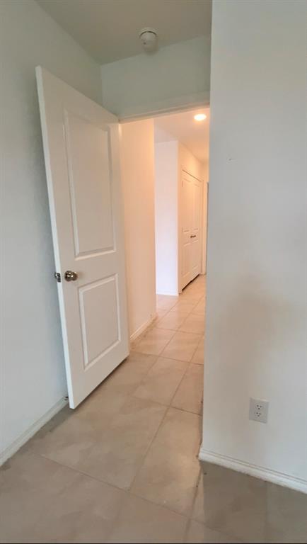 Interior corridor featuring light-toned tile flooring, white two-panel doors, and recessed lighting