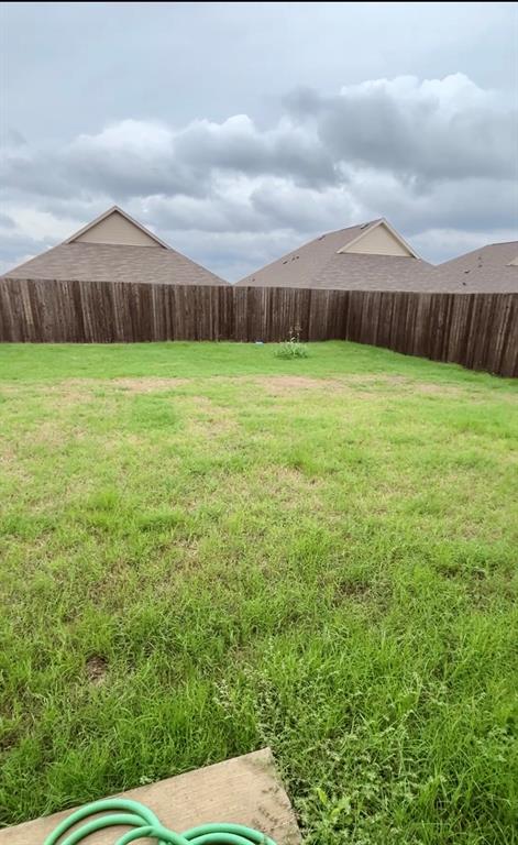 Open backyard featuring a grass lawn and wood privacy fencing