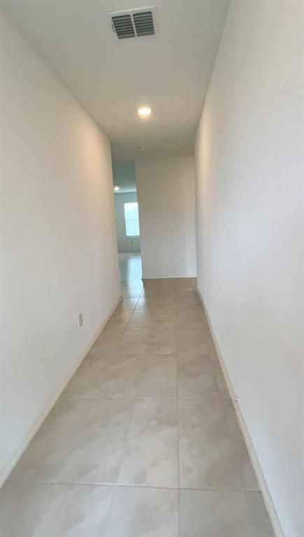 Neutral-toned ceramic tile flooring, high ceilings, and recessed lighting