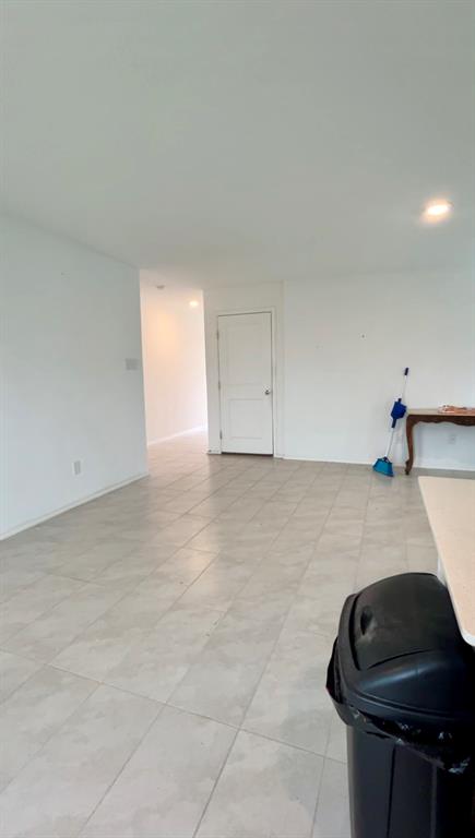 Interior space featuring large-format ceramic tile flooring, recessed lighting, and a solid-core panel door