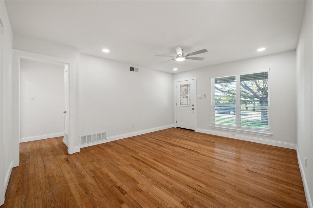 Wood-finish flooring, recessed lighting, ceiling fan with integrated light, and an exterior door featuring a glass inset