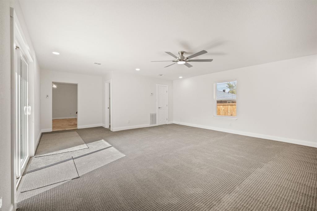 Neutral-toned carpet, recessed lighting, brushed-nickel ceiling fan, and sliding glass door
