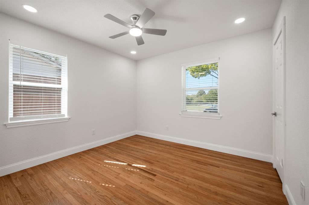 Room featuring wood-finish flooring, recessed lighting, a modern ceiling fan, and multiple windows with horizontal blinds