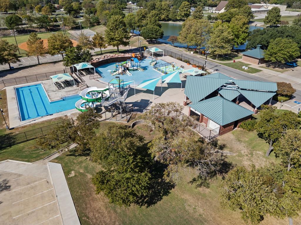 Community aquatic facility featuring a lap pool, water slide, splash pad, shaded structures, and metal roofing Community aquatic facility featuring a lap pool, water slide, splash pad, shaded structures, and metal roofing