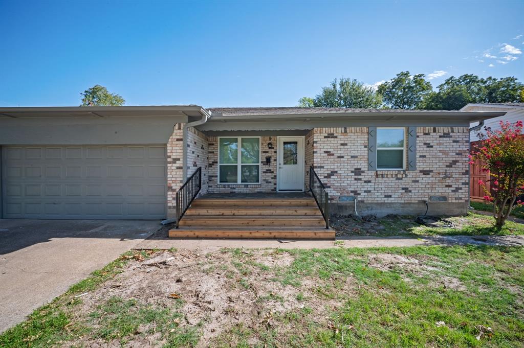 Single-story exterior featuring multi-toned brick masonry, wood-plank front steps, metal handrails, and an attached two-car garage Single-story exterior featuring multi-toned brick masonry, wood-plank front steps, metal handrails, and an attached two-car garage