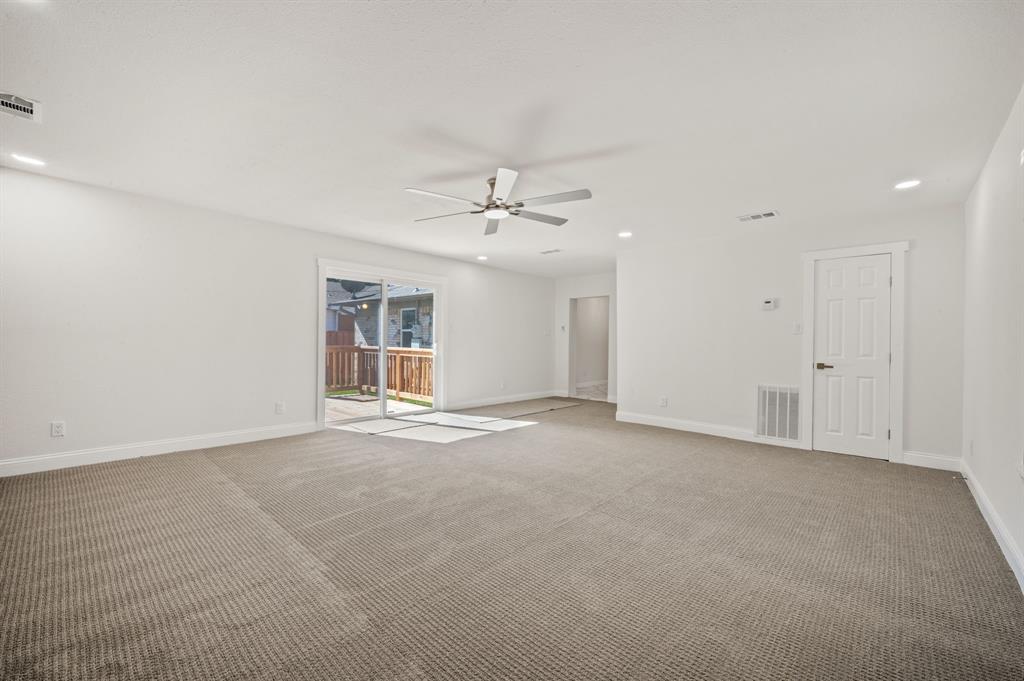 Neutral-toned wall-to-wall carpeting, recessed ceiling lighting, central ceiling fan, and sliding glass doors to exterior patio space