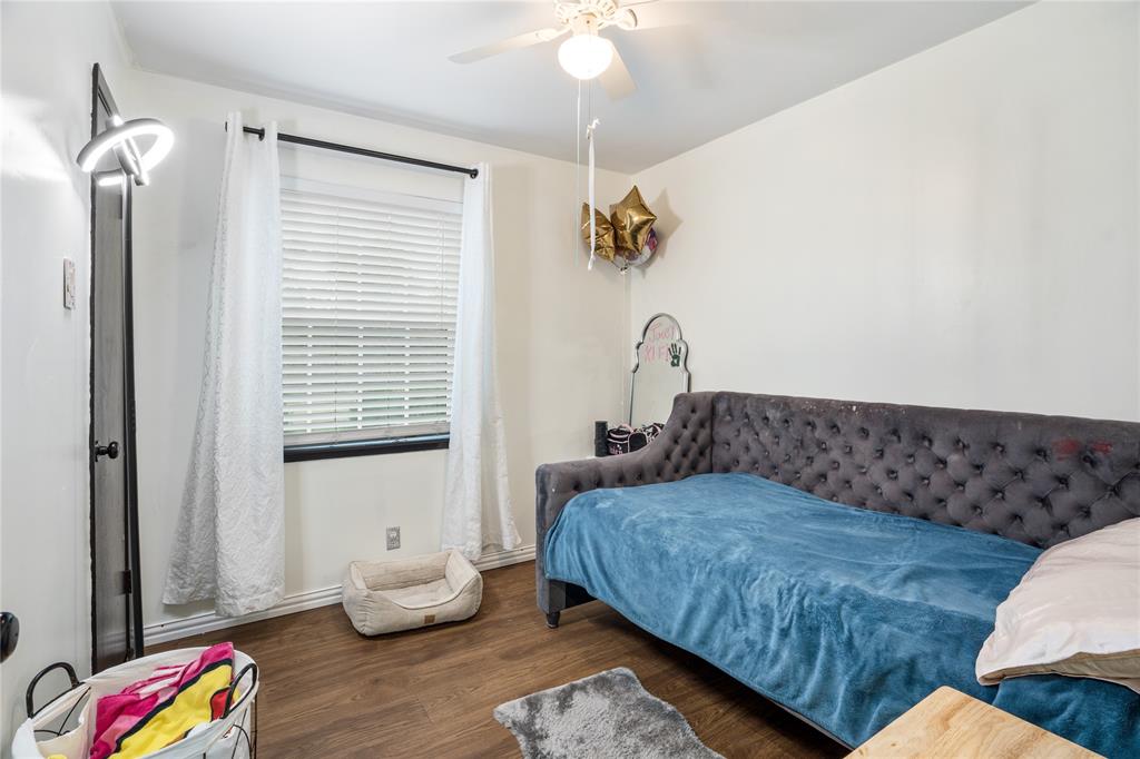 Wood-finish flooring, horizontal window blinds, and a white ceiling fan with integrated lighting Wood-finish flooring, horizontal window blinds, and a white ceiling fan with integrated lighting