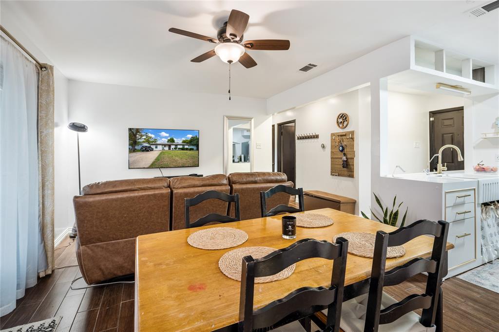 Wood-finish flooring, ceiling fan with integrated light fixture, and white cabinetry with a farmhouse sink Wood-finish flooring, ceiling fan with integrated light fixture, and white cabinetry with a farmhouse sink