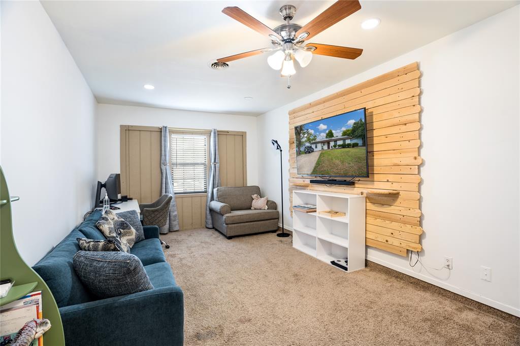 Room featuring a natural wood-plank accent wall, recessed lighting, and a ceiling fan with integrated light fixture