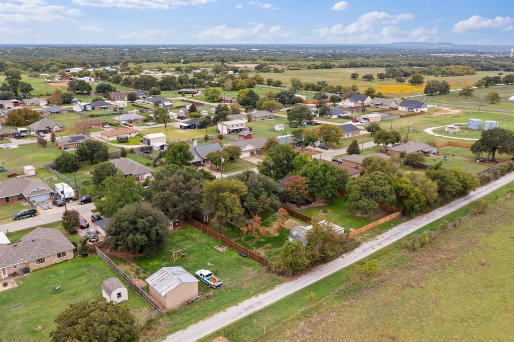 Aerial perspective featuring expansive acreage, mature tree canopy, fenced perimeter, and detached metal storage structure