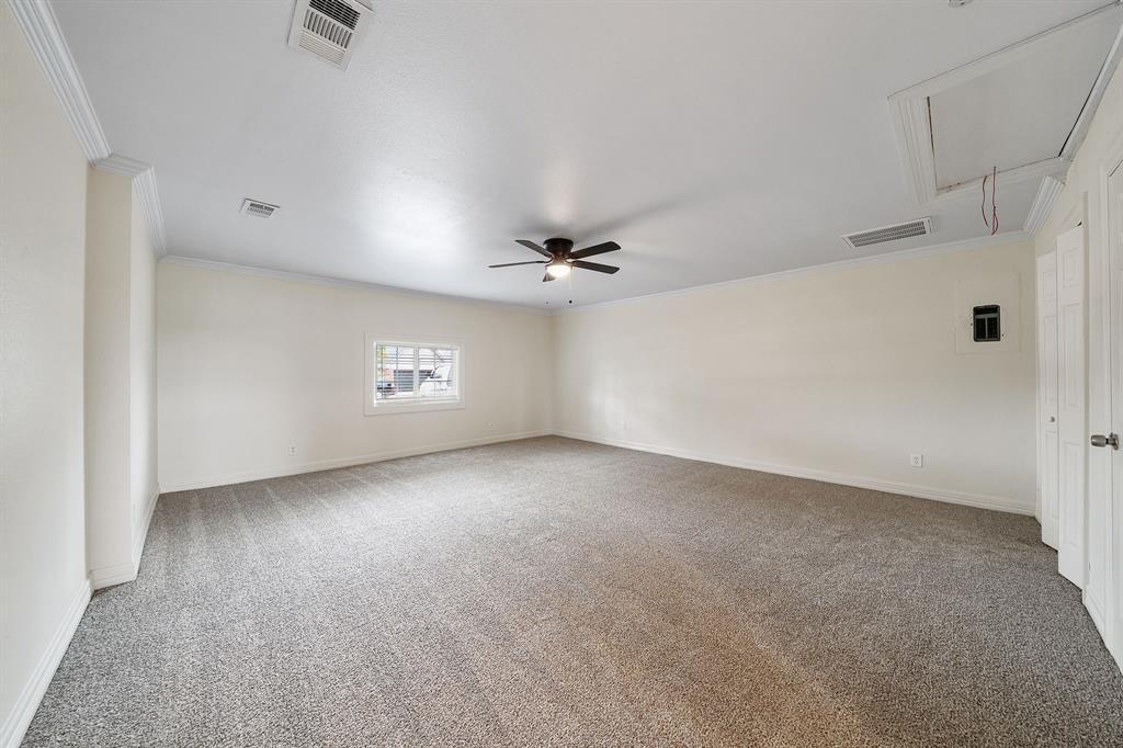 Neutral-toned interior space featuring wall-to-wall carpeting, crown molding, a central ceiling fan, and double-door closet storage