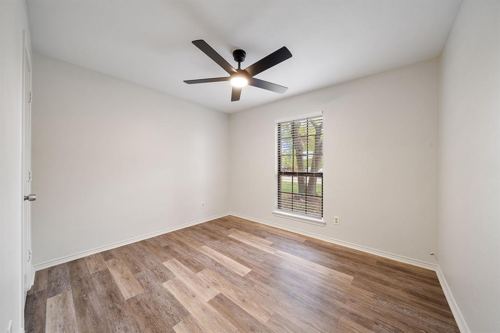 Room featuring wood-finish flooring, a matte black multi-blade ceiling fan with integrated lighting, and a single-pane window