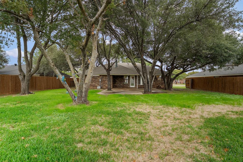 Backyard featuring mature trees, a concrete patio, and perimeter wood fencing