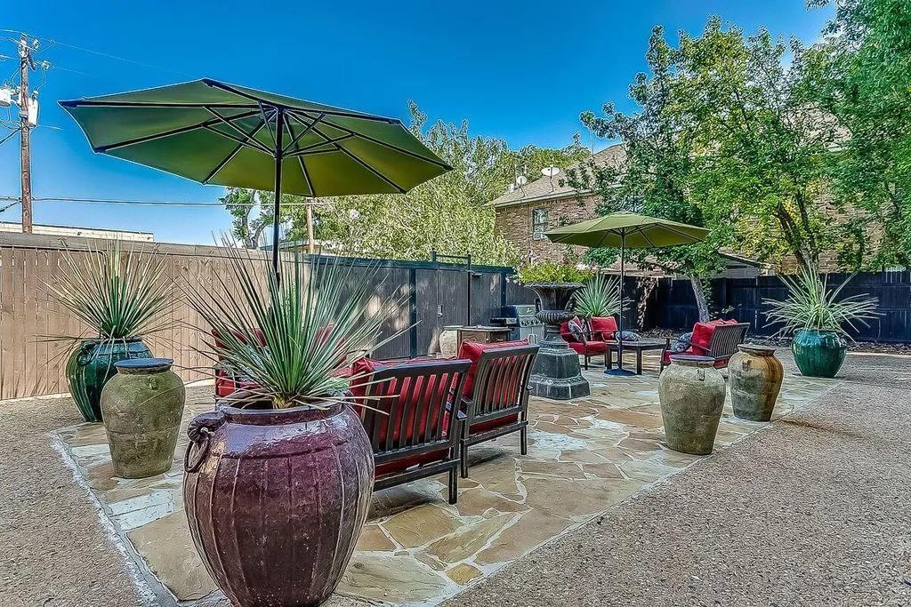Flagstone patio featuring gravel ground cover, perimeter wood fencing, and decorative stone urns