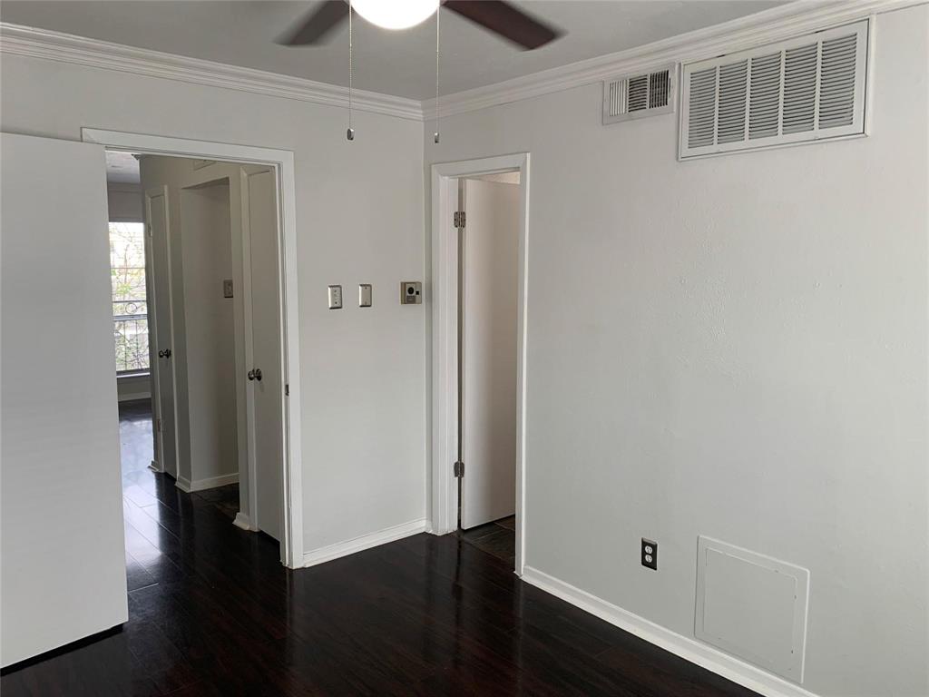 Dark wood-finish flooring, neutral wall paint, and overhead ceiling fan with integrated lighting
