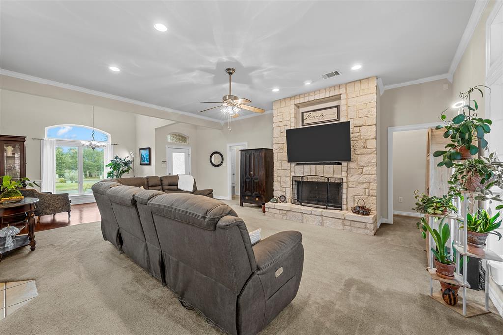 Floor-to-ceiling natural stone fireplace with a raised hearth, recessed lighting, arched window with transom, and ceiling fan Floor-to-ceiling natural stone fireplace with a raised hearth, recessed lighting, arched window with transom, and ceiling fan