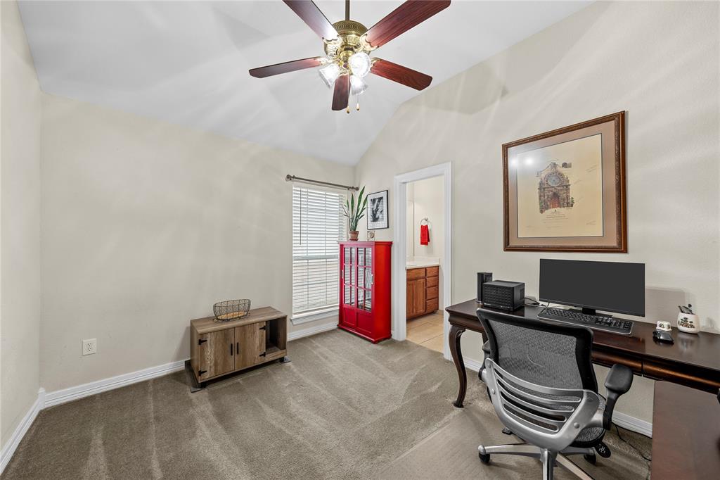 Vaulted ceiling featuring a central multi-blade ceiling fan with integrated light fixture, neutral wall palette, carpeting, and a single window with slatted blinds