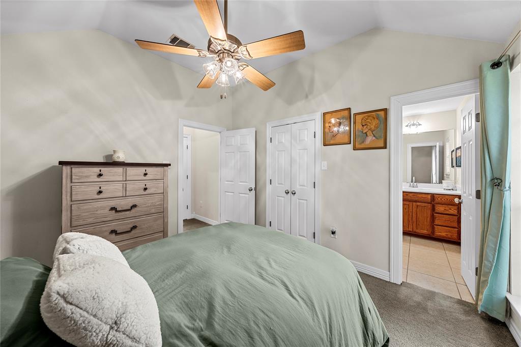 Vaulted ceiling, multi-blade ceiling fan with integrated lighting, dual-panel closet doors, and wood-finish cabinetry