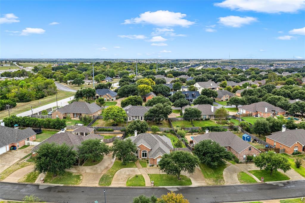 Aerial perspective of a suburban neighborhood featuring brick masonry homes, composition shingle roofs, concrete driveways, and established tree canopy