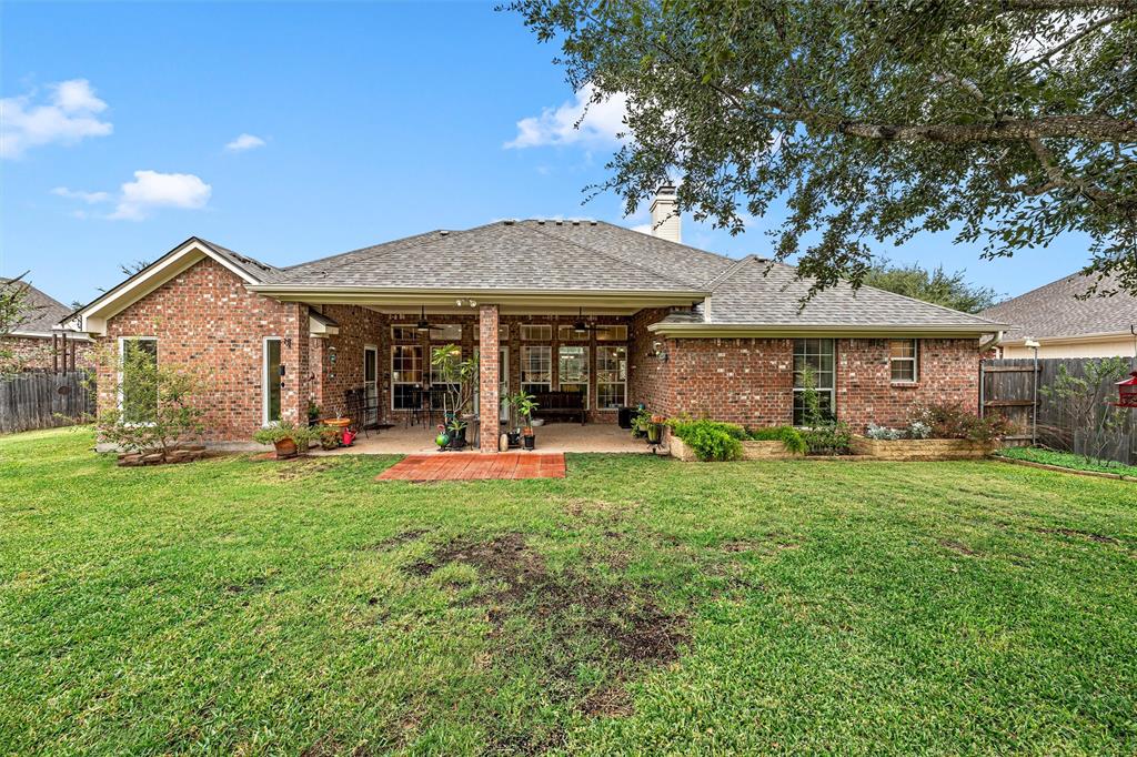 Brick exterior featuring a covered patio, paved hardscaping, raised masonry planter beds, and a fenced backyard
