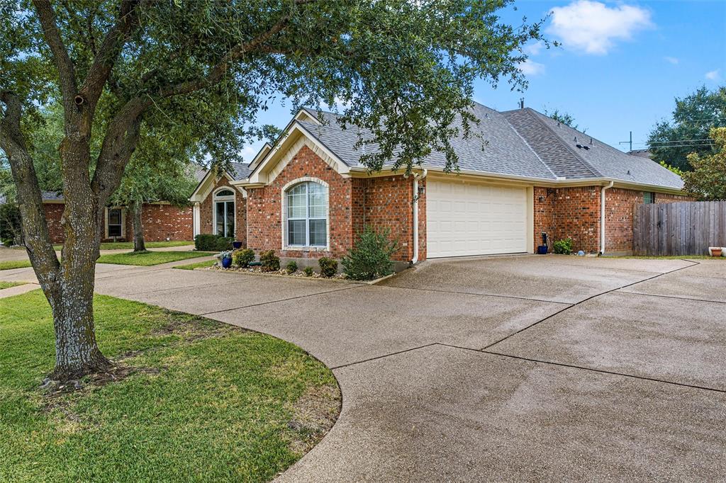 Single-story brick exterior with a gabled roofline, multi-car garage, expansive concrete driveway, and mature landscaping Single-story brick exterior with a gabled roofline, multi-car garage, expansive concrete driveway, and mature landscaping