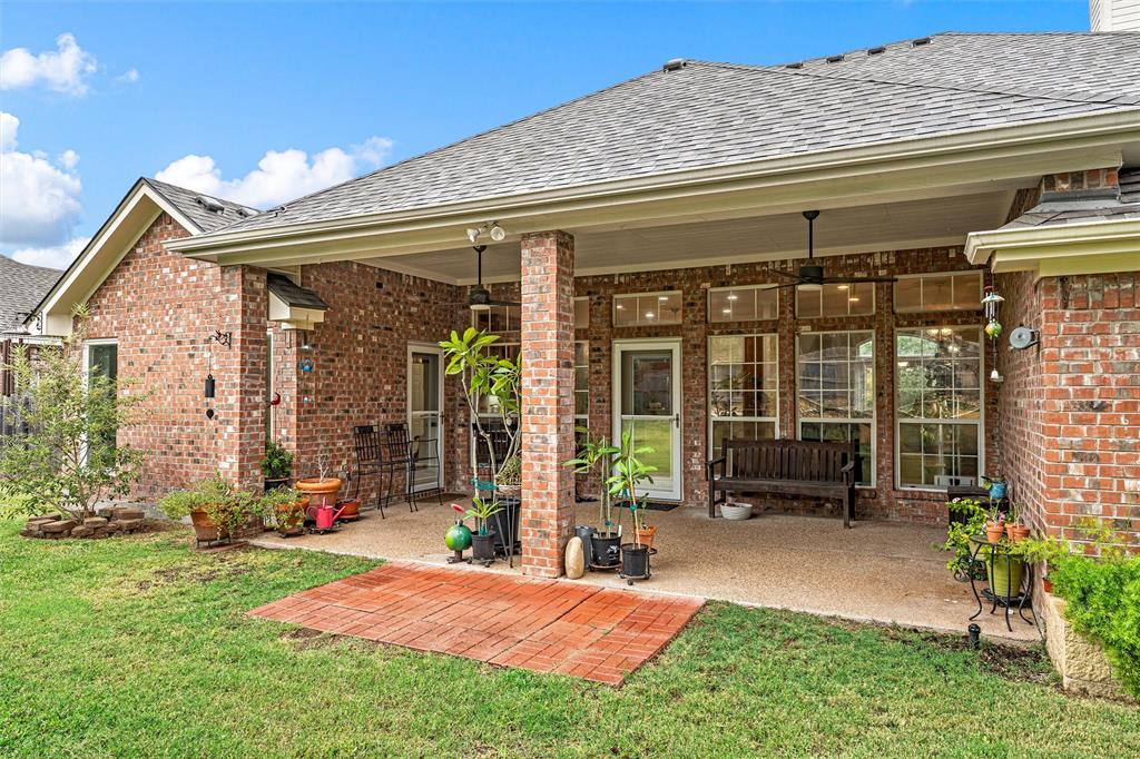 Covered rear patio featuring brick masonry construction, a textured concrete floor, recessed ceiling lighting, and integrated ceiling fans