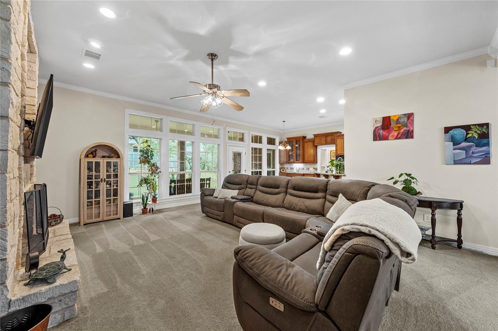 Floor-to-ceiling stone fireplace, series of large multi-pane windows, recessed ceiling lighting, ceiling fan with integrated light fixture, and arched built-in cabinetry Floor-to-ceiling stone fireplace, series of large multi-pane windows, recessed ceiling lighting, ceiling fan with integrated light fixture, and arched built-in cabinetry