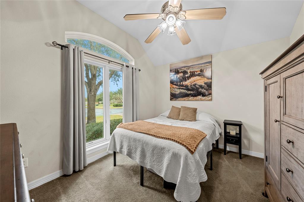 Vaulted ceiling featuring a ceiling fan with integrated light fixtures, arched window with decorative trim, and wall-to-wall carpeting