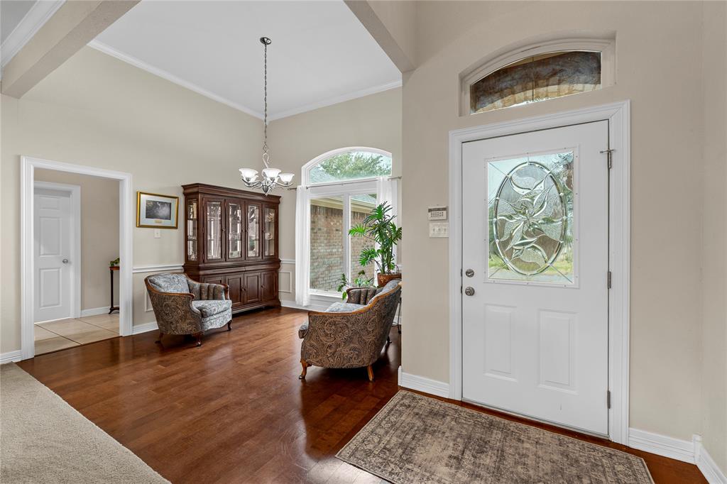Entryway featuring vaulted ceilings, wood-finish flooring, an arched window, and an entry door with an oval decorative glass insert and transom window Entryway featuring vaulted ceilings, wood-finish flooring, an arched window, and an entry door with an oval decorative glass insert and transom window