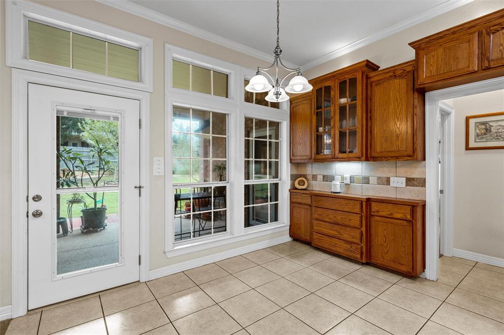 Custom-built wood cabinetry with glass-front display doors, ceramic tile flooring, multi-light chandelier, and large windows with transom detailing