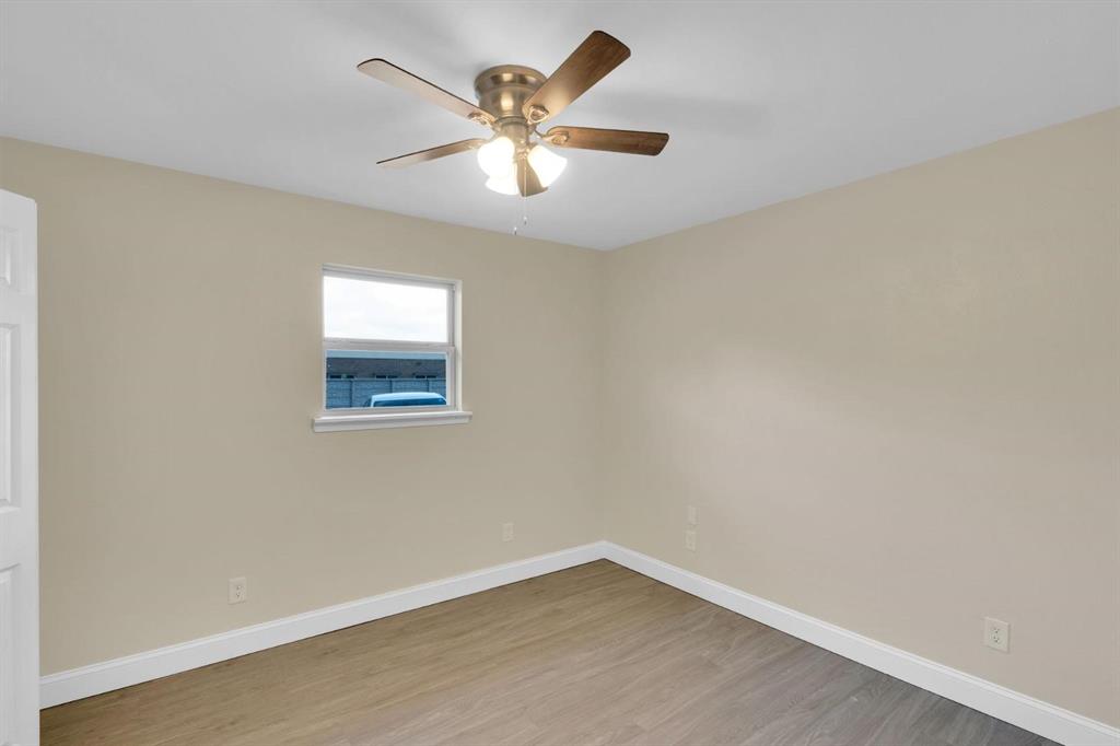 Room featuring neutral-toned walls, wood-finish flooring, a single-hung window, and a ceiling fan with integrated lighting