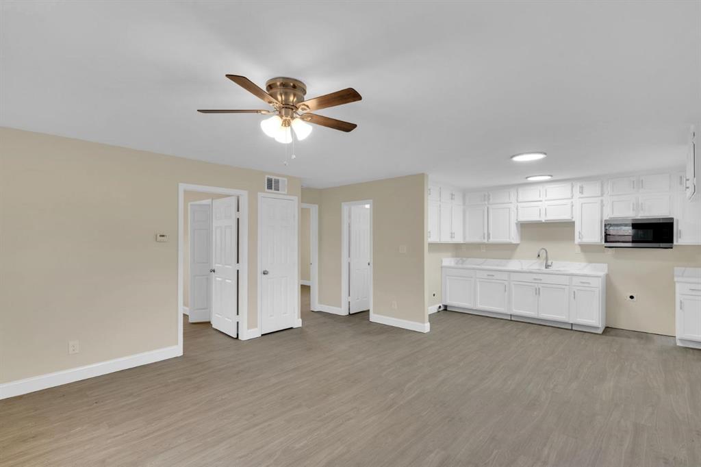Wood-finish flooring, white cabinetry, integrated microwave, multi-light ceiling fan, and recessed lighting