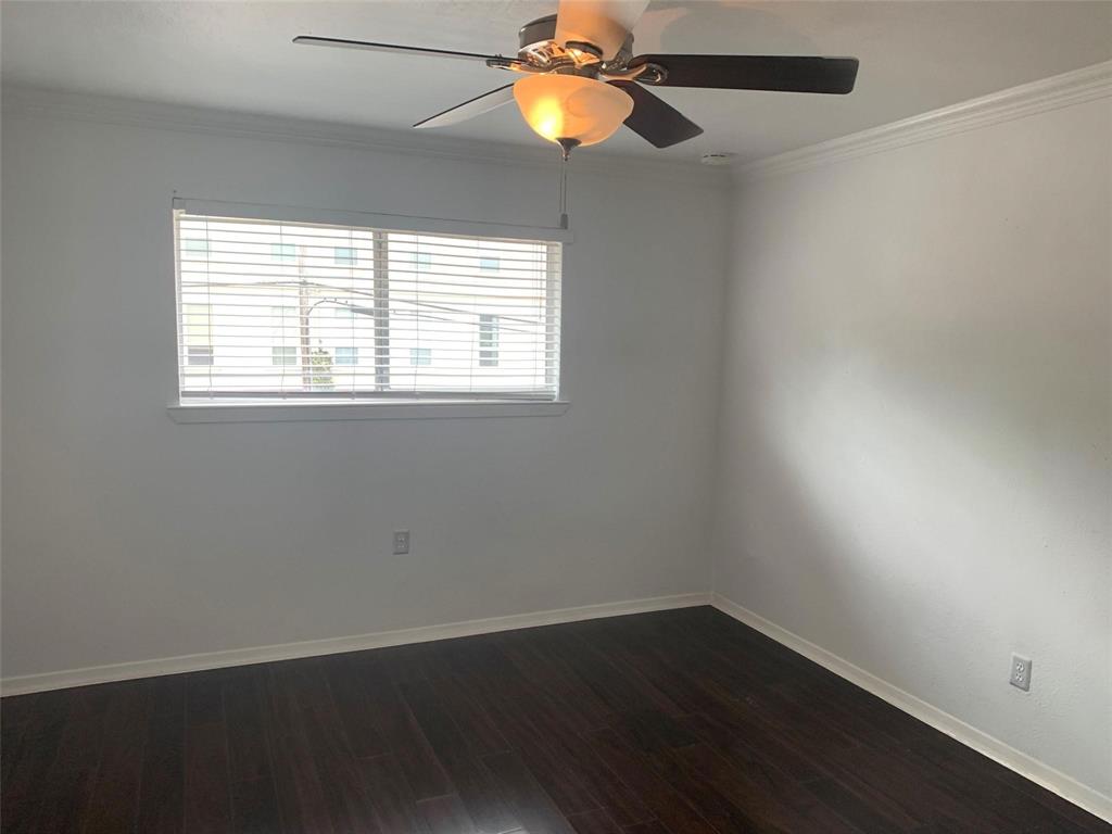 Dark wood-finish flooring, neutral wall tones, multi-blade ceiling fan with integrated lighting, and horizontal window blinds