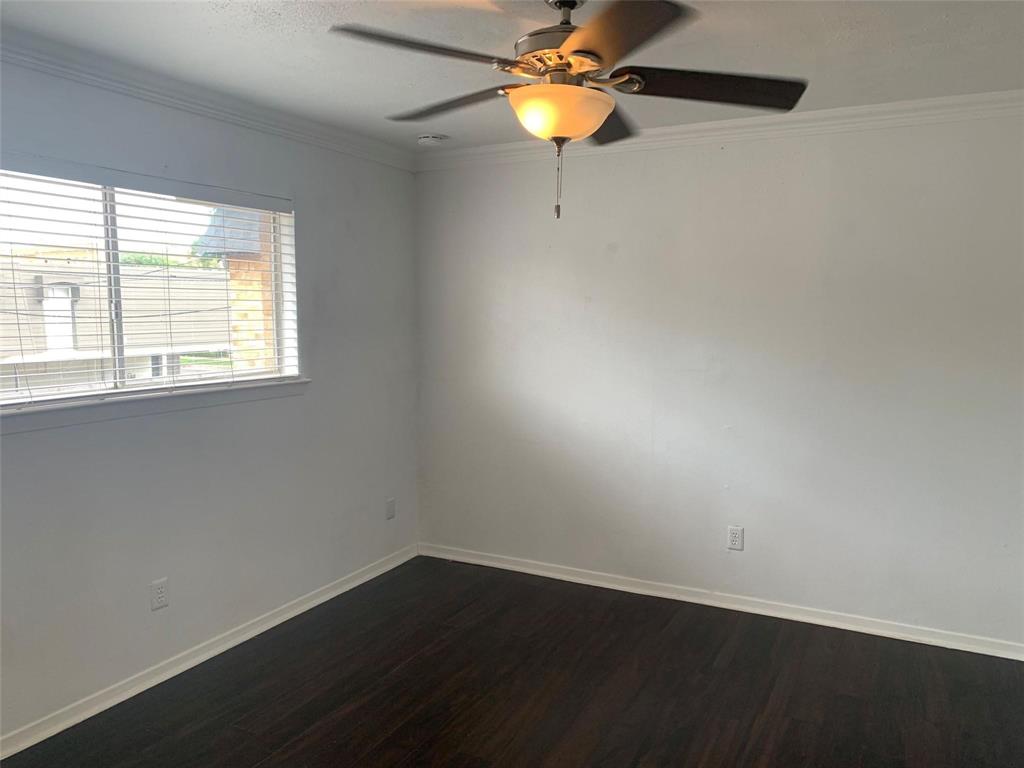 Room featuring dark wood-finish flooring, white walls, crown molding, horizontal blinds, and a ceiling fan with integrated lighting