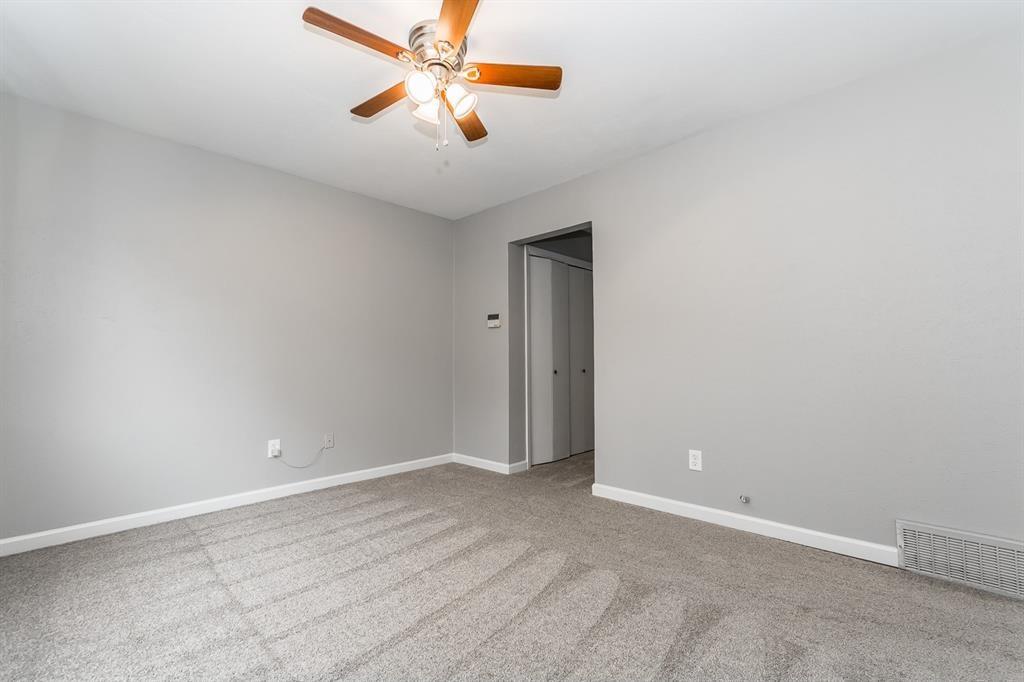 Neutral-toned interior room featuring wall-to-wall carpeting and a ceiling fan with integrated light fixtures