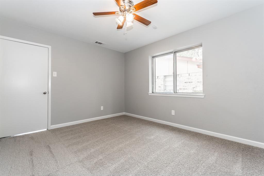 Neutral-toned interior space featuring wall-to-wall carpeting, a multi-blade ceiling fan with integrated lighting, and a dual-pane sliding window