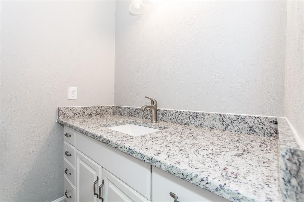 White vanity featuring a stone-composite countertop, undermount sink, brushed nickel faucet, and brushed nickel hardware