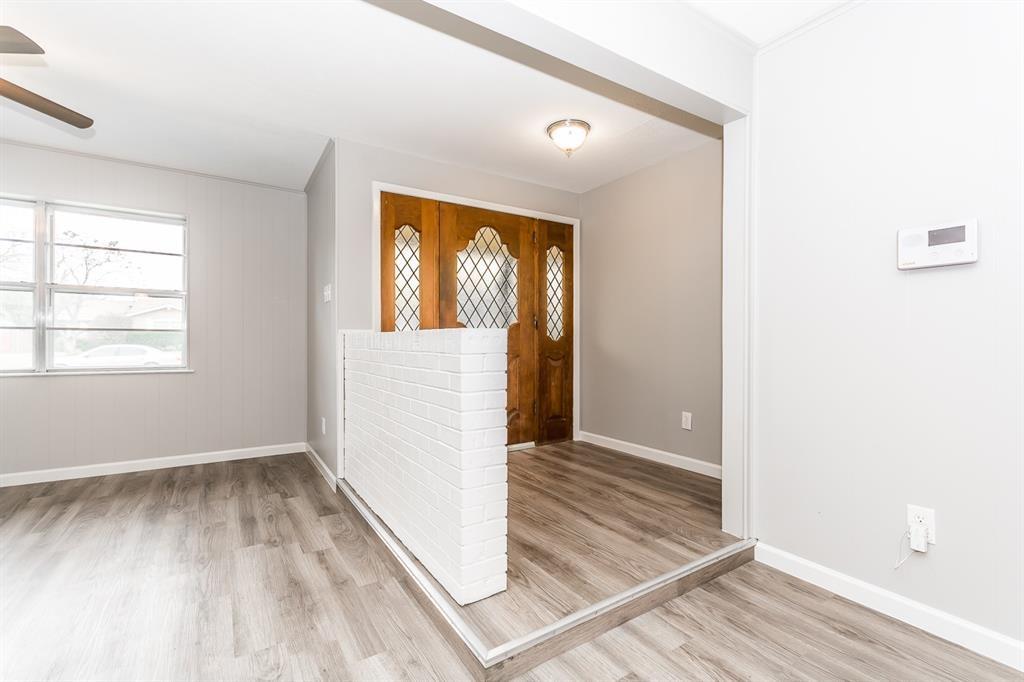 Entryway featuring a wood front door with diamond-patterned glass inserts, a white painted brick half-wall divider, wood-finish flooring, and a flush-mount ceiling light fixture