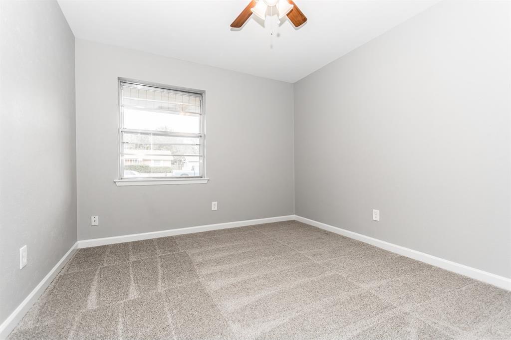 Neutral-toned interior featuring wall-to-wall carpeting, a multi-pane window, and a ceiling-mounted light fixture with a fan