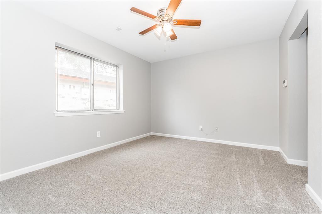 Neutral-toned walls, wall-to-wall carpeting, window with horizontal blinds, and a ceiling fan with integrated light fixture